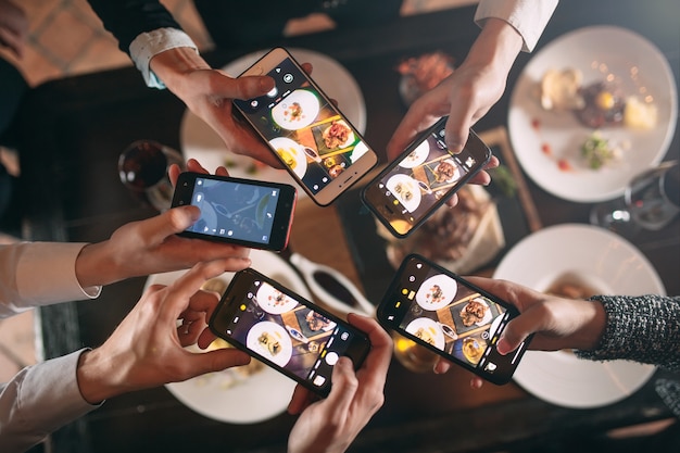 Group of friends going out and taking a photo of food together with mobile phone