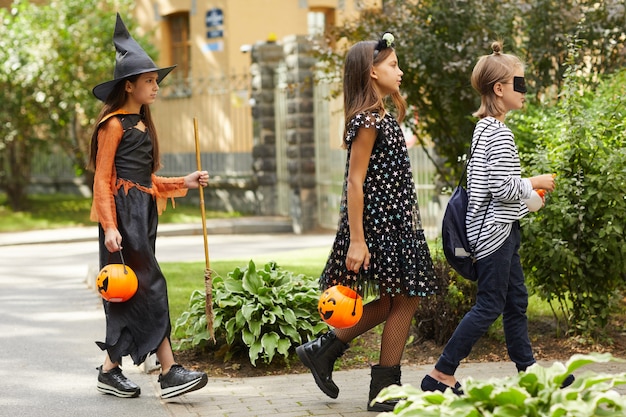 Group of friends in Halloween costumes walking along the street they want treats