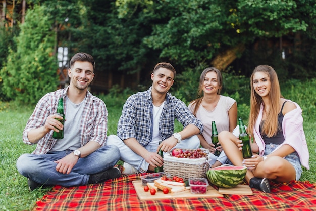 Group of friends have a fun. Joyful girls and guys spend weekend outdoor on picnic in the park