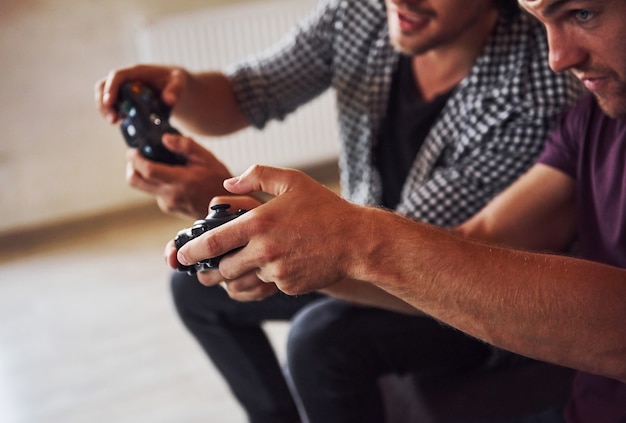 Group of friends have fun playing console game indoors at living room.