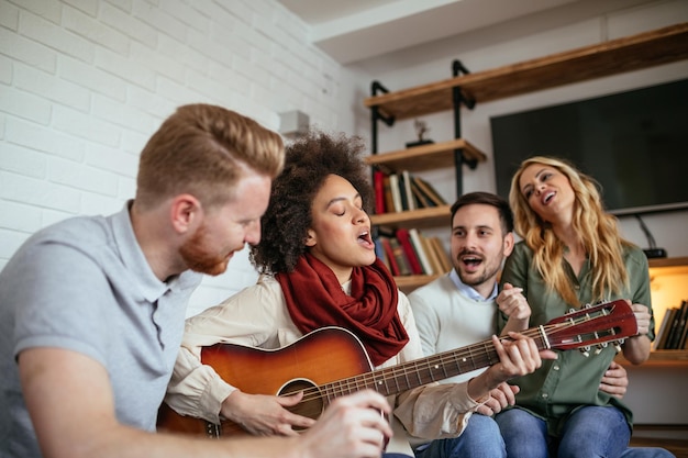 Photo group of friends having fun playing a guitar and singing