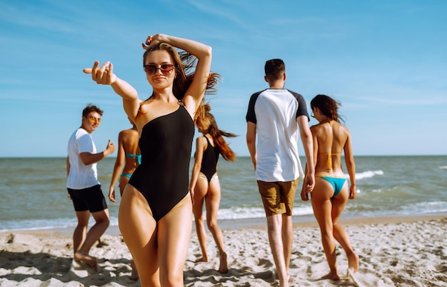 Photo group of friends having fun running along beach young friends enjoying on beach holiday summertime