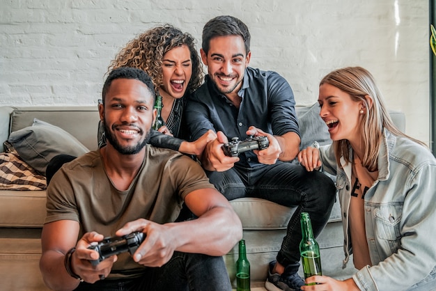 Playful friends playing video games online and having fun Stock