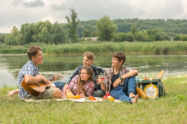 Gruppo di amici che hanno un picnic vicino al fiume