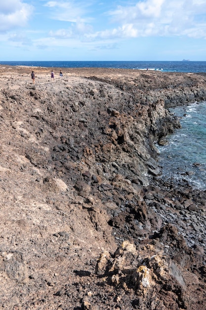 Group of friends hiking along the cliffs and unspoiled beaches on the island of La Graciosa, Canary