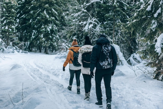 group of friends hiking on snowy path in forest