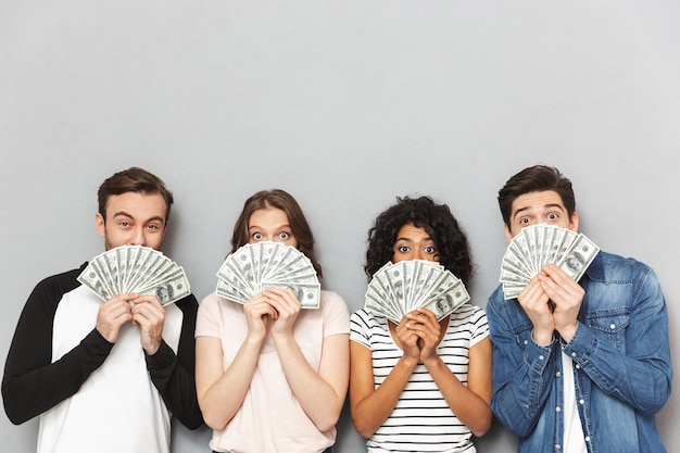 Group of friends holding money covering faces.