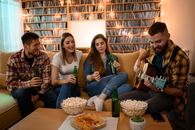 ギターを弾き、ビールを飲みながらホーム パーティーに参加している友人のグループ