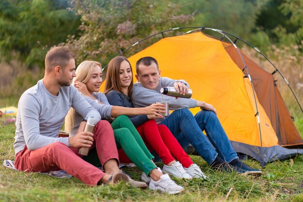 A group of friends is enjoying a warming drink from a thermos