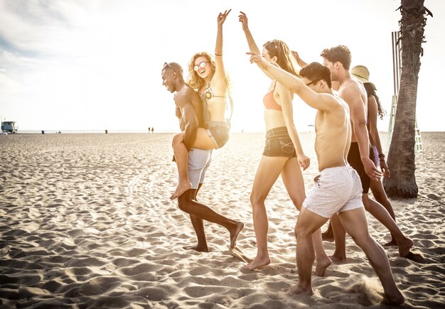 Group of friends making big party and games on the beach