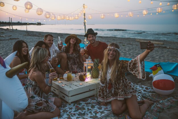 Foto gruppo di amici che fanno festa sulla spiaggia al momento del tramonto