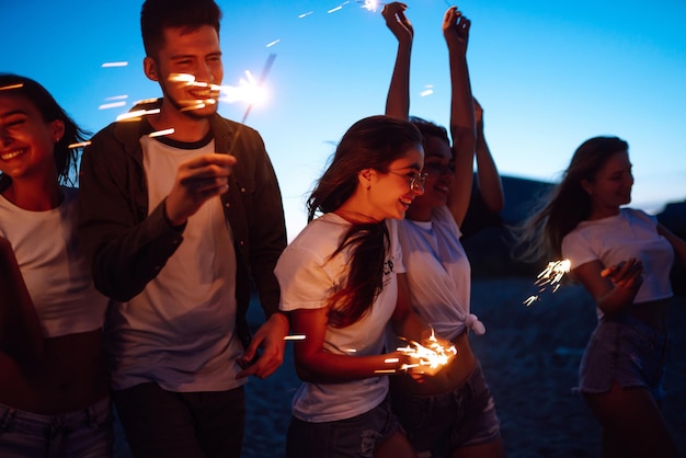 폭죽과 해변에서 밤에 친구의 그룹 해변 휴가를 즐기는 젊은 친구