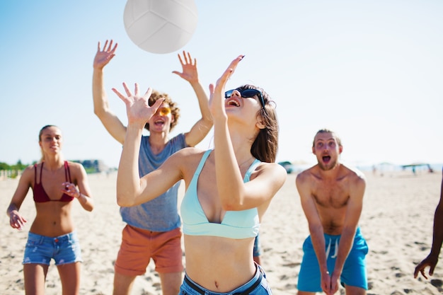 Gruppo di amici che giocano a beach volley in spiaggia