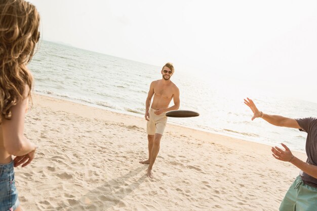 Group of friends playing gliding disc at the beach