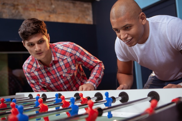 Group of friends playing table soccer at beer pub