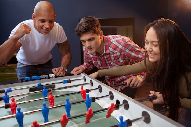 Group of friends playing table soccer at beer pub