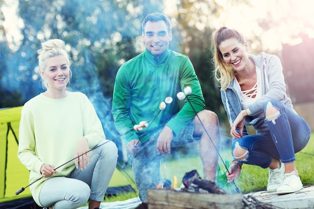 group of friends preparing marshmallow on campfire