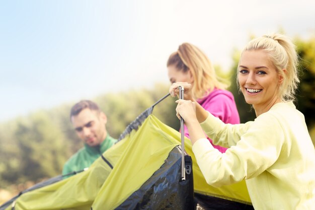 Group of friends putting up tent in the forest