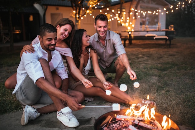 Group of friends roasting marshmallows over fire