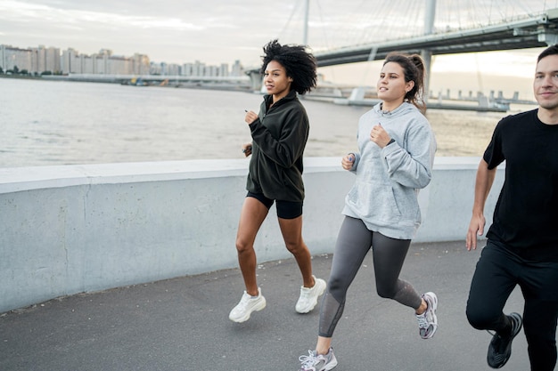 Group of friends runners training fast running in sportswear\
and sneakers