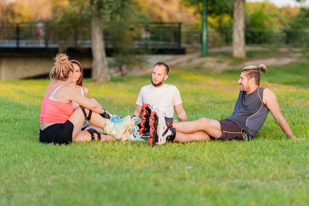 Group of friends sitting in a circle in a park with inline skates