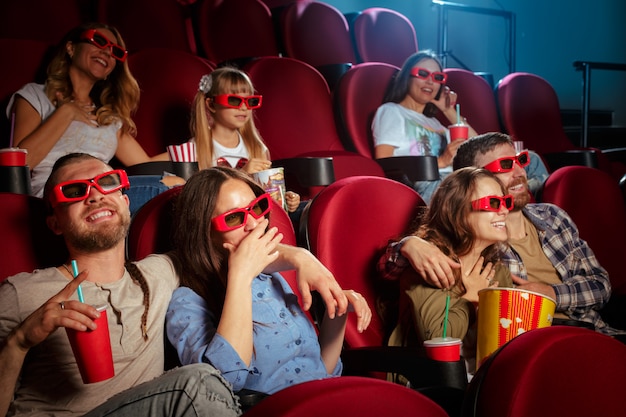 ポップコーンと飲み物の映画館に座っている友人のグループ