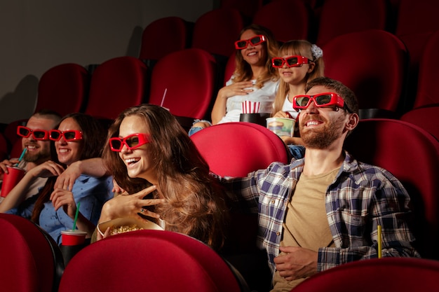 Group of friends sitting in movie theater with popcorn and drinks