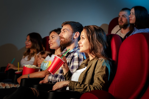 ポップコーンと飲み物の映画館に座っている友人のグループ