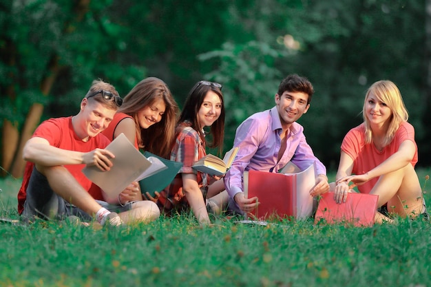 Gruppo di studenti di amici seduti sull'erba nel parco