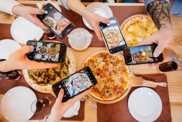 Un gruppo di amici scatta una foto ravvicinata di una deliziosa pizza per il blog, pizzeria.