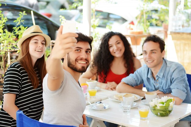 Group of friends taking selfie in cafe