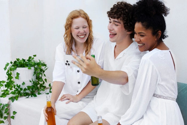 Photo group of friends taking selfie during a white party with drinks