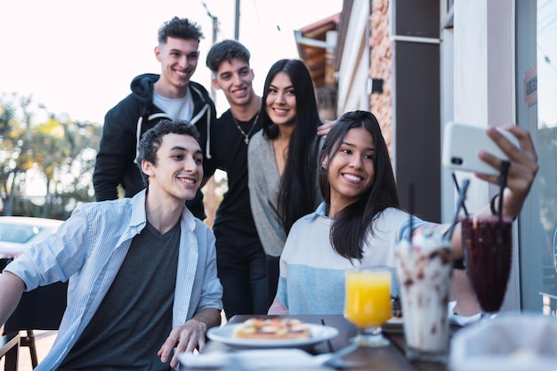 Photo group of friends taking a selfie at an outdoor bar.