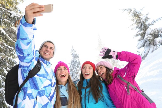 Foto gruppo di amici che prendono selfie al resort nevoso vacanze invernali