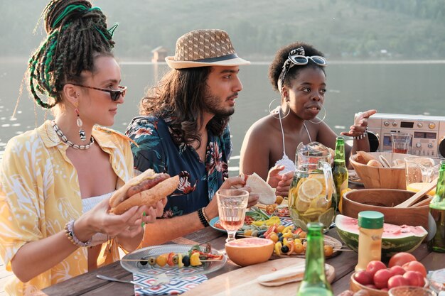 Gruppo di amici che parlano tra loro seduti al tavolo durante il pranzo all'aperto