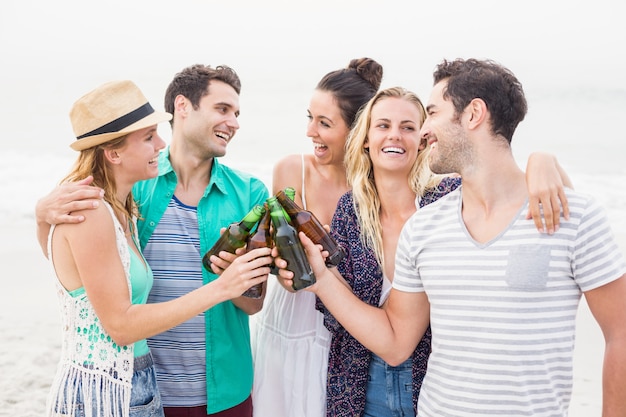 Group of friends toasting beer bottles on the beach