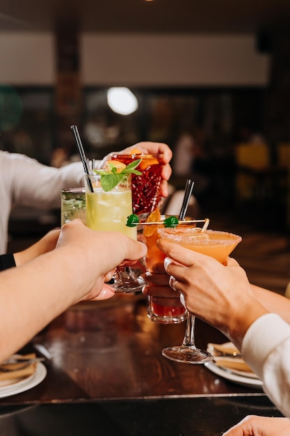 活気のあるバーでコクテルを飲んで一緒に乾杯する友達のグループ