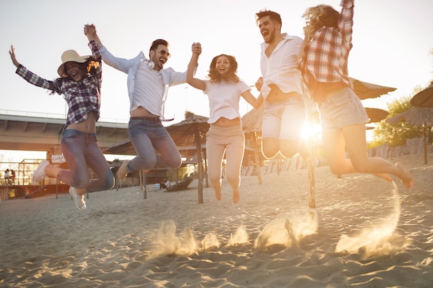 Group of friends together on beach jumping and having fun