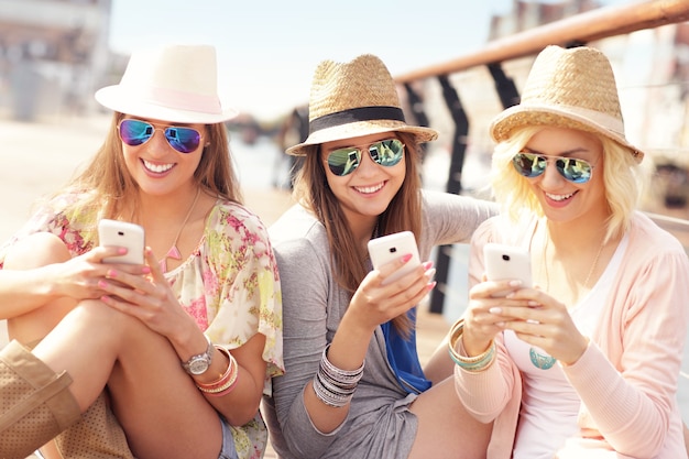 group of friends using smartphones in the city