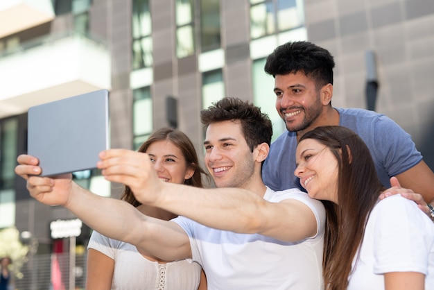 Group of friends using their tablet to take a selfie