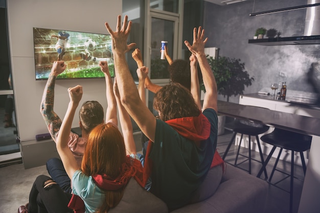 Photo group of friends watch the game together on television and rejoice