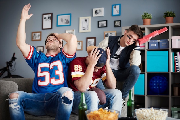 Photo group of friends watching football at home