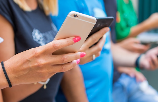 Foto gruppo di amici che guardano i telefoni cellulari intelligenti - generazione dei millennial