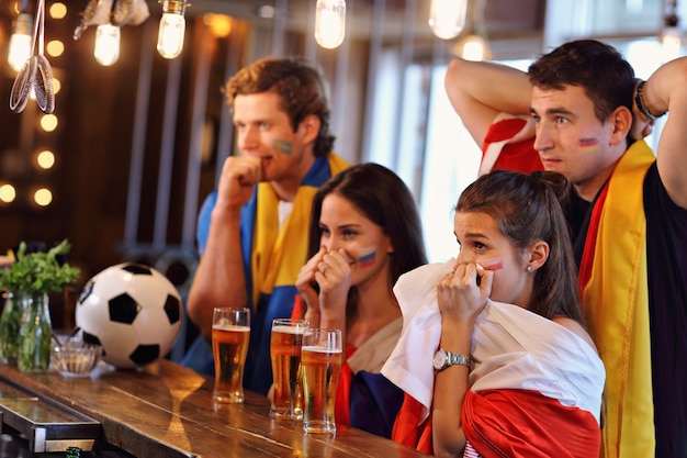 Group of friends watching soccer game in pub