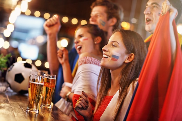 Group of friends watching soccer game in pub