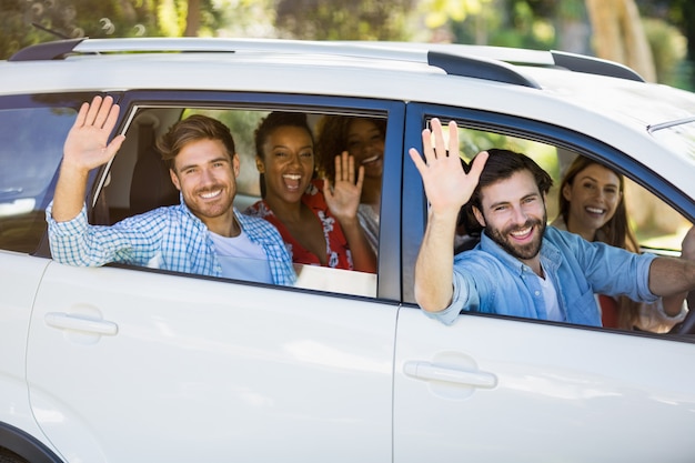 Group of friends waving hands from car