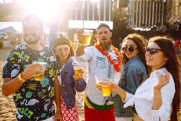 Group of friends with beer dancing and having fun at music festival together Summer Beach party