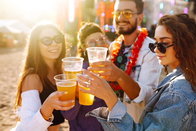 Group of friends with beer dancing and having fun at music festival togetherCelebration concept