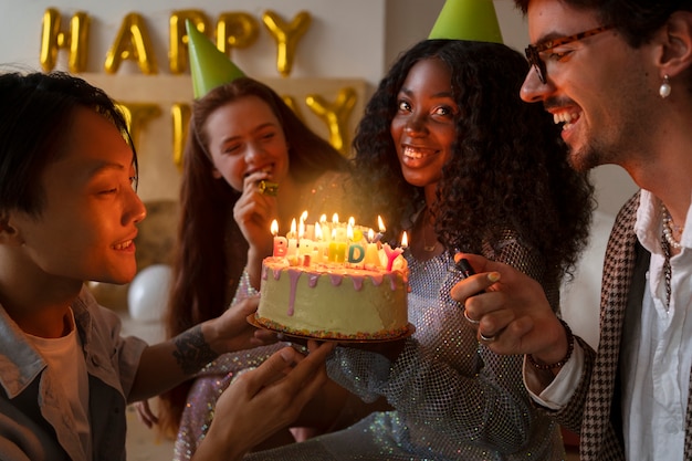 Gruppo di amici con torta a una festa di compleanno a sorpresa