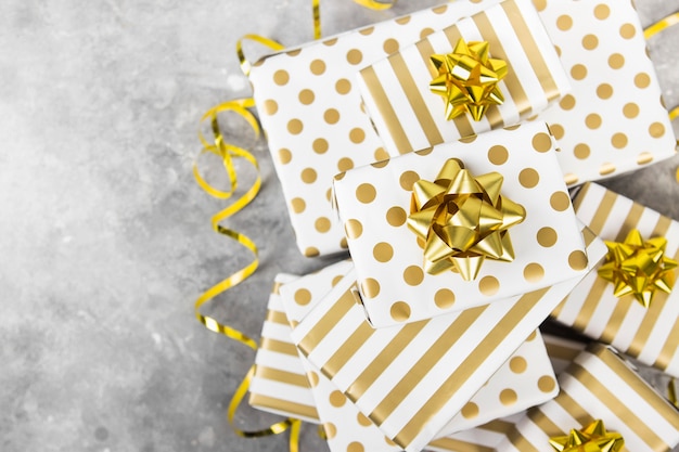 Group of gifts in white and gold paper on a gray surface